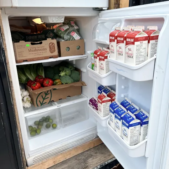 A white fridge full of a variety fresh produce and diary products.
