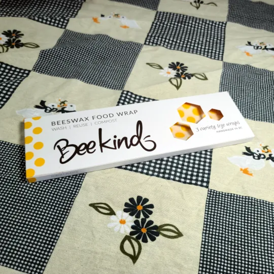 BeeKind beeswax food wrap variety pack box sitting on top of table cloth.