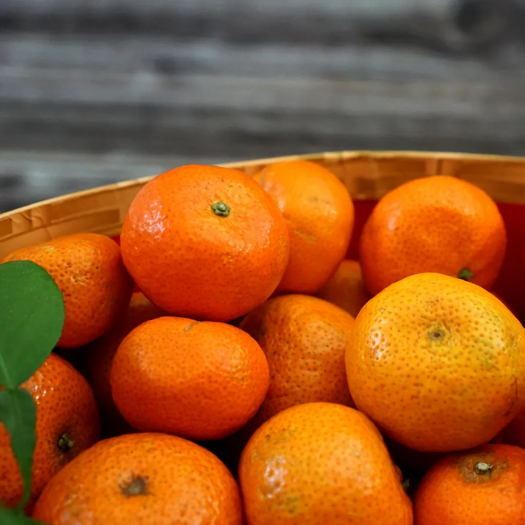 A wooden bowl full of Chinese mandarin oranges