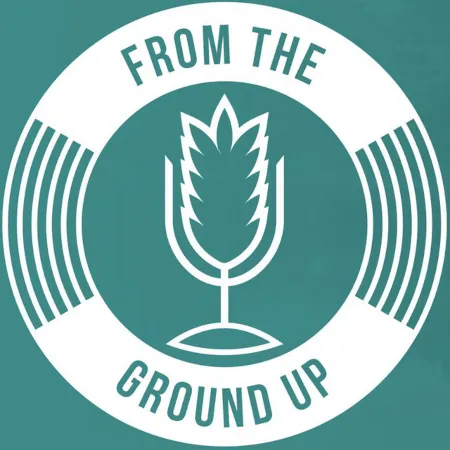 The show logo for From the Ground Up. Log is a white circle with sound waves on the left and right side with a white grain in the shape of a microphone in the middle, and text at the top of the circle 'From The' and bottom of the circle, 'Ground Up'.