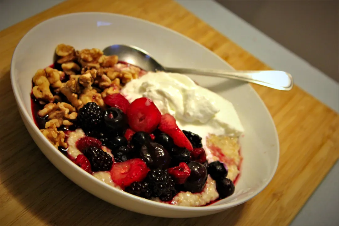 A bowl full of gluten-free steel cut oats, California nuts, organic fruit berry blend and plain yogurt.