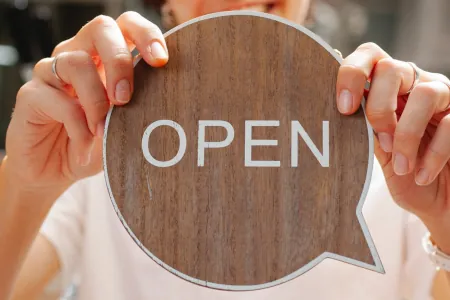 Woman smiling while holding an open sign by Tim Douglas on Pexels