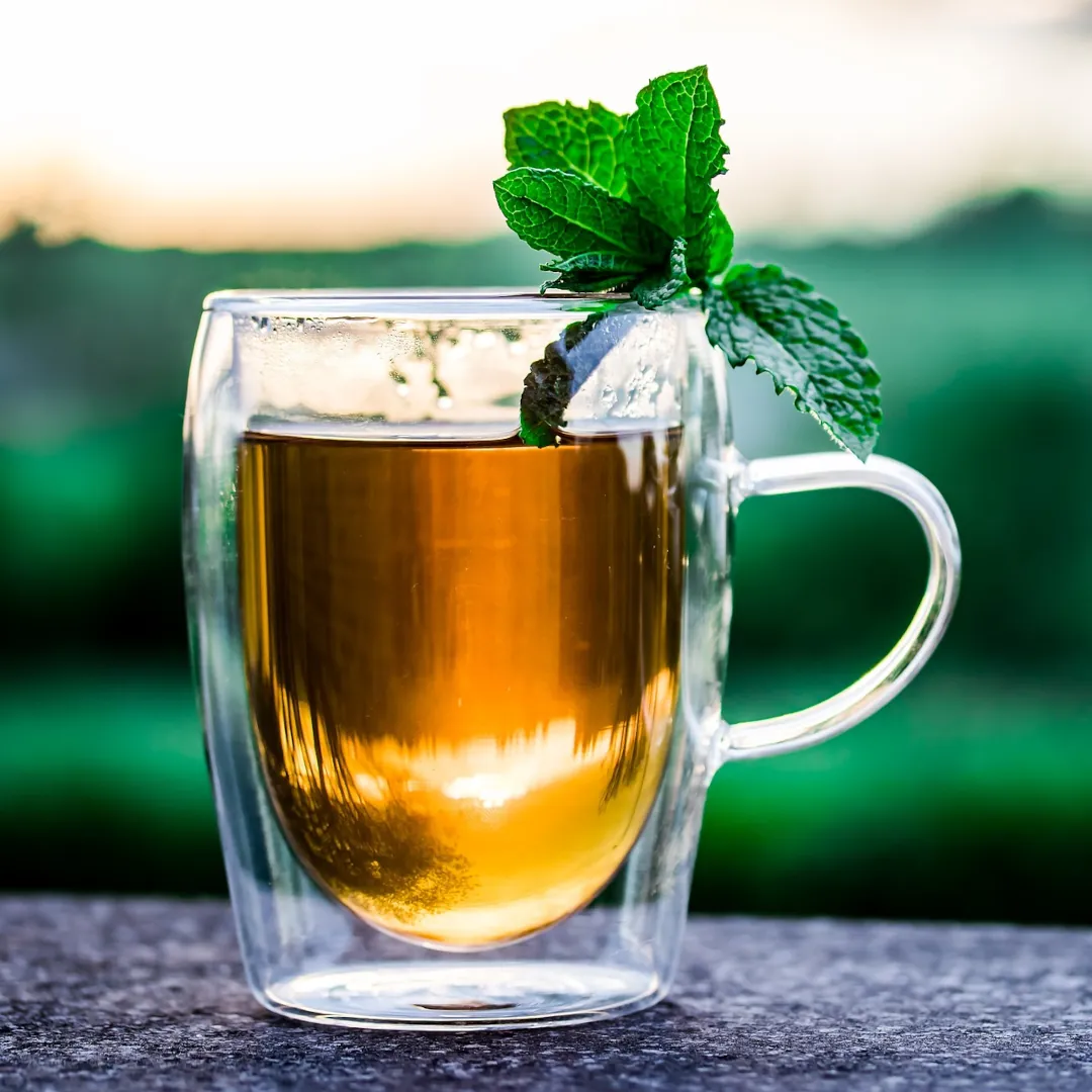 A hot cup of tea on a table against a green space background