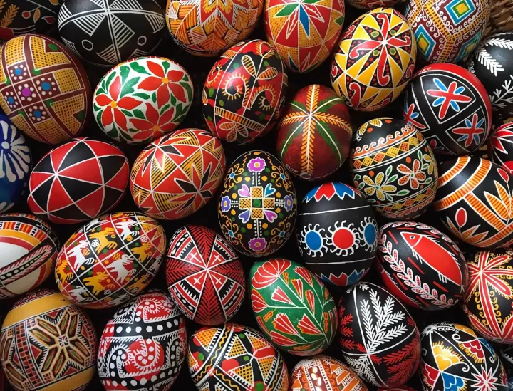 An over the top view of a collection of Ukrainian easter eggs decorated in vibrant colours and various designs.